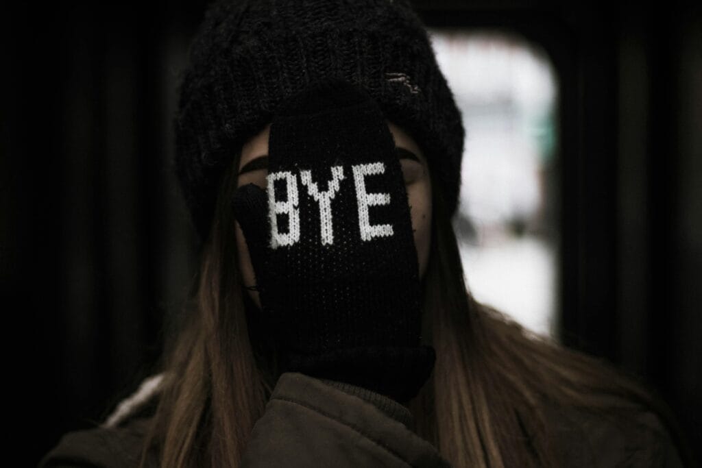 Portrait of a young woman wearing a hat and glove with 'Bye' text, expressing a playful farewell.